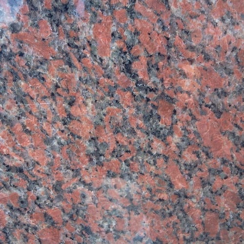 Red Aswan granite slab face, photographed for the factory catalog — mid-toned red overall.