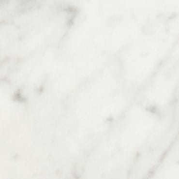 Bianco Carrara B marble slab face, photographed for the factory catalog — near-white warm beige overall.
